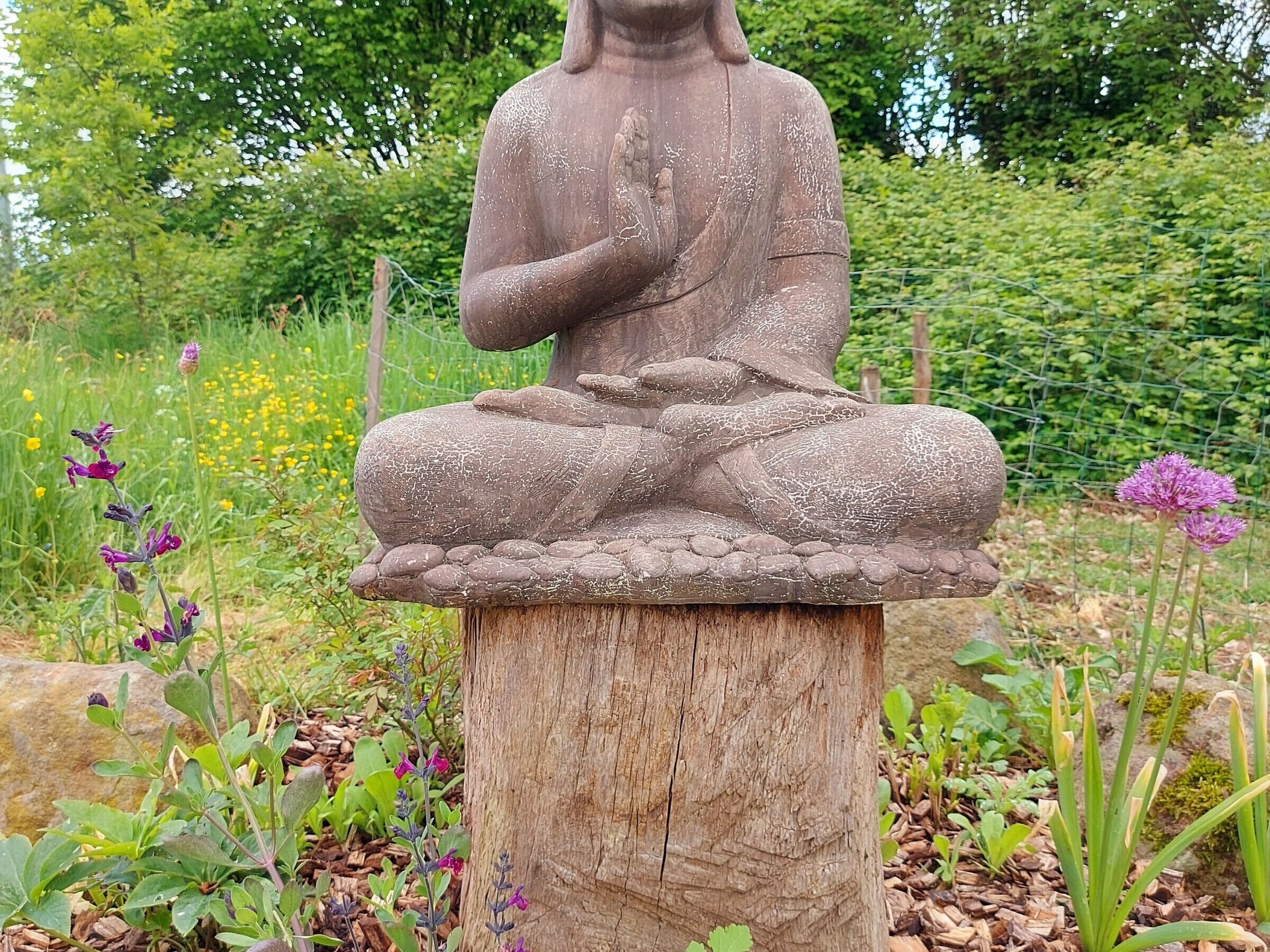 Una statua di Buddha in pietra in un giardino.
