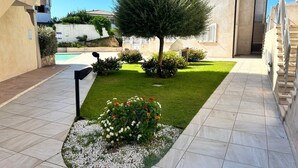A courtyard with a swimming pool, a small tree, and a flower bed. - 2 Bedroom Apartment in Palau (Palau)