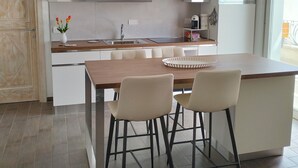 A modern kitchen with white cabinetry, a wooden dining table, and two bar stools. - 2 Bedroom Apartment in Palau (Palau)