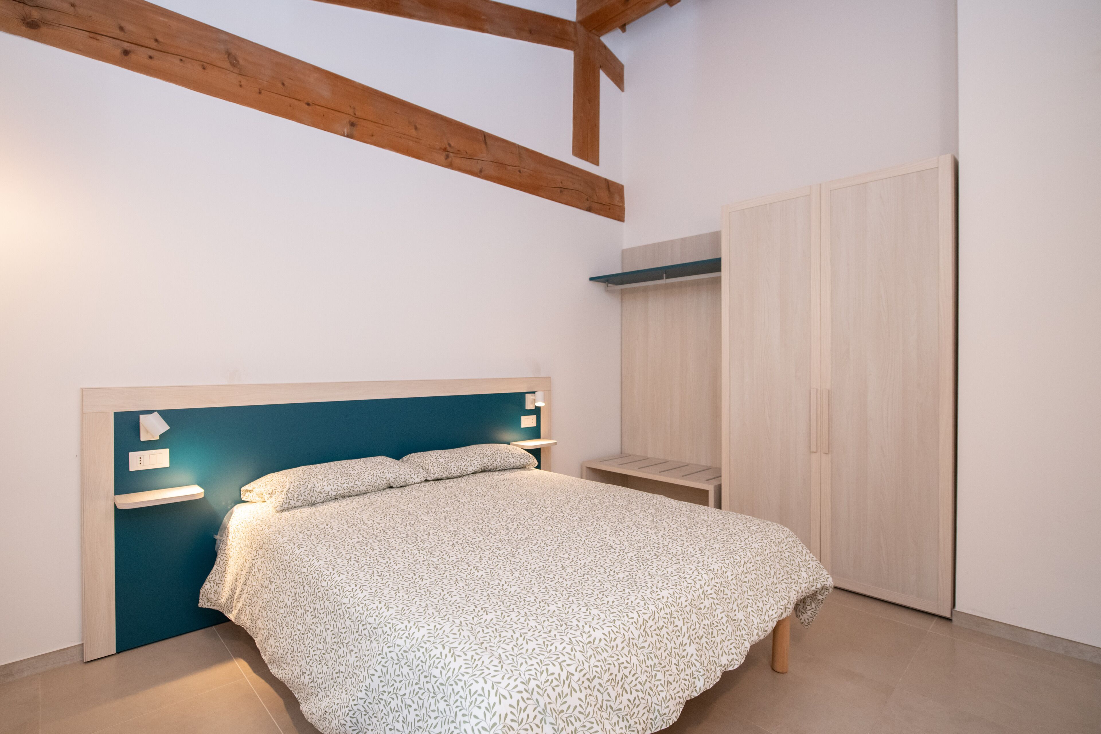 Un dormitorio con cama, armario y mesita de noche.