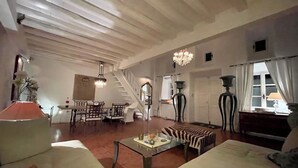 Un vaste salon doté d’un haut plafond, d’un escalier, d’un lustre et d’un coin repas.