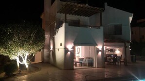 Edificio de dos pisos con un patio, zona de comedor y piscina visible.
