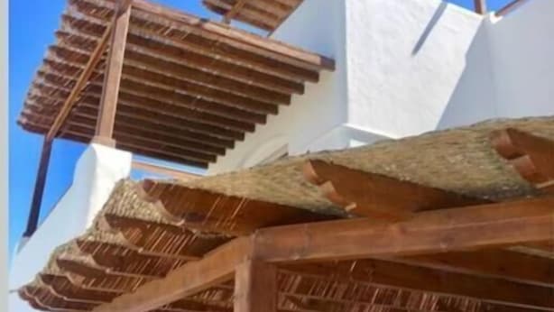 Un edificio blanco con una estructura de pérgola de madera.