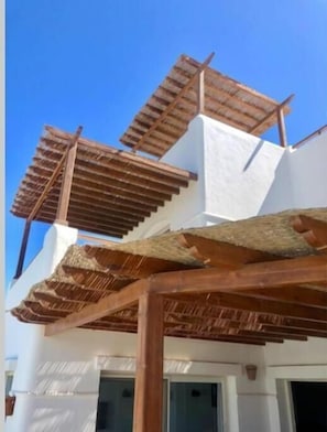 Un edificio blanco con una estructura de pérgola de madera.