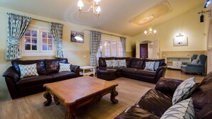 A spacious living room with leather sofas, a wooden coffee table, and a chandelier. - Villa Freesia with heated pool and free air con (Oasis del Sur)