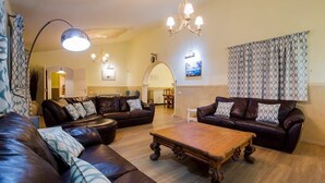 A living room with leather sofas, a wooden coffee table, and a chandelier. - Villa Freesia with heated pool and free air con (Oasis del Sur)