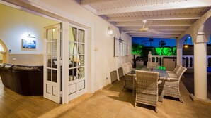 A spacious indoor area with a dining table and chairs, a leather couch, and a glass door leading outside. - Villa Freesia with heated pool and free air con (Oasis del Sur)