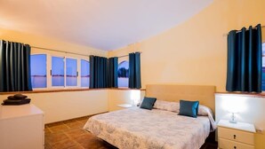 A bedroom with a large bed, two bedside tables, a dresser, and a window with curtains. - Villa Freesia with heated pool and free air con (Oasis del Sur)