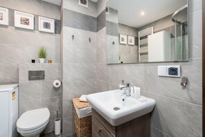 A modern bathroom with a white sink, a toilet, and a shower area.