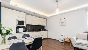 Une cuisine moderne avec des meubles blancs, un four à micro-ondes encastré et un coin repas avec une table dressée pour deux personnes.