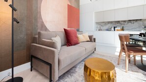 A modern living room with a sofa, a round gold side table, and a large abstract wall art piece. - Stylish Apartment with Balcony | Parking | View of the Motława River (Gdansk)
