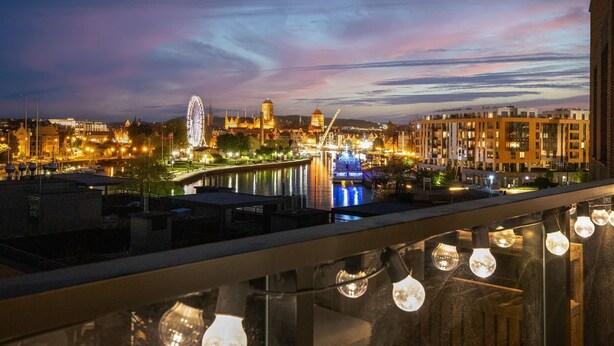 A cityscape at dusk with illuminated buildings, a river, and a Ferris wheel. - Stylish Apartment with Balcony | Parking | View of the Motława River (Gdansk)