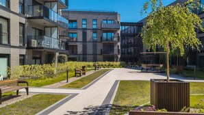 A modern residential building with balconies, a central courtyard with benches, and a tree. - Stylish Apartment with Balcony | Parking | View of the Motława River (Gdansk)