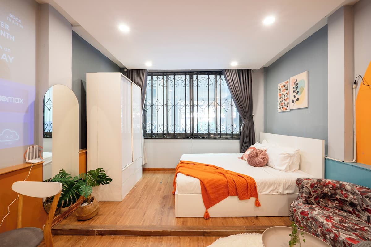 A modern bedroom with a bed, a sofa, a desk, and a window with curtains.