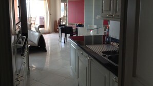 A modern kitchen with white cabinets, a dining area with a table and chairs, and a living room with a sofa and a TV. - Penthouse near Saint Tropez Cavalaire sur mer Port view, Beach... (Cavalaire-sur-Mer)