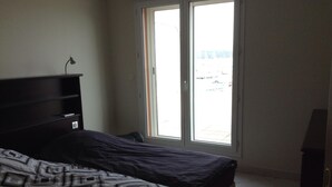 A bedroom with a bed, a nightstand, a desk, and a window with a view of the outside. - Penthouse near Saint Tropez Cavalaire sur mer Port view, Beach... (Cavalaire-sur-Mer)