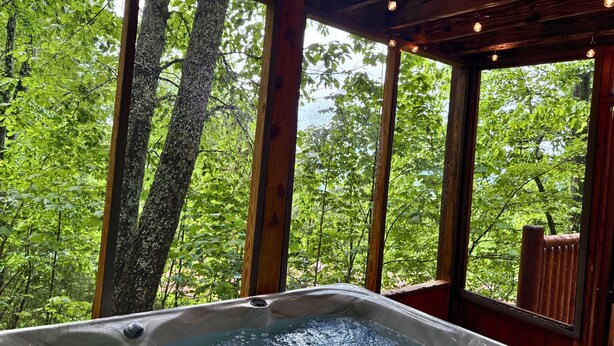 A hot tub with a view of a forest through large windows. - Relax Above the Smokies · Bearway to Heaven (Sevierville)