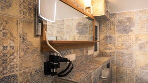 A bathroom with a tiled wall, a wooden shelf, and a mounted camera. - Ferienwohnung Esswiese (Weimar)
