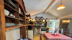 A cozy kitchen with wooden shelves, a dining table with a checkered tablecloth, and a hanging pendant light. - Ferienwohnung Esswiese (Weimar)