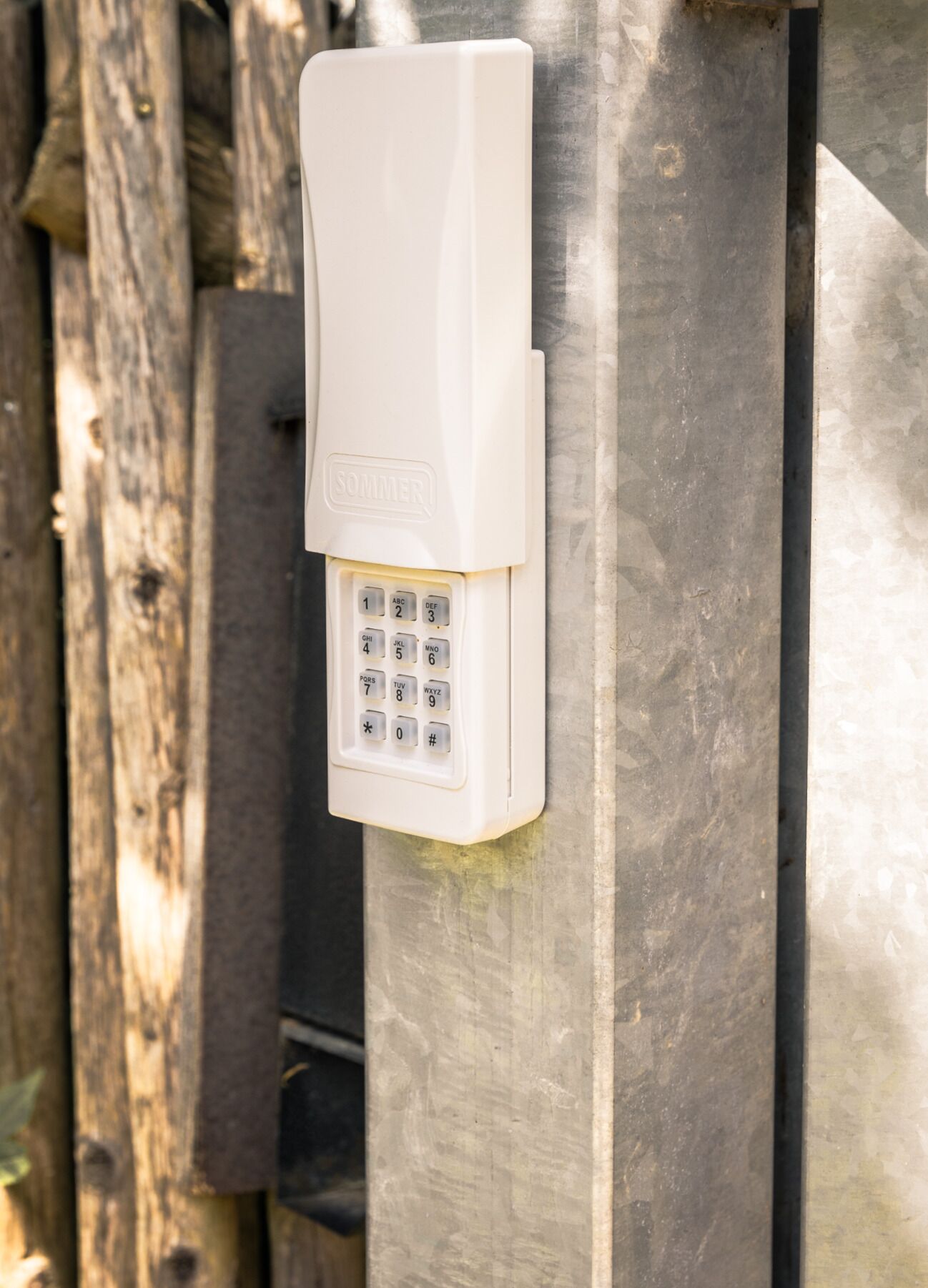 A white outdoor intercom mounted on a metal surface.