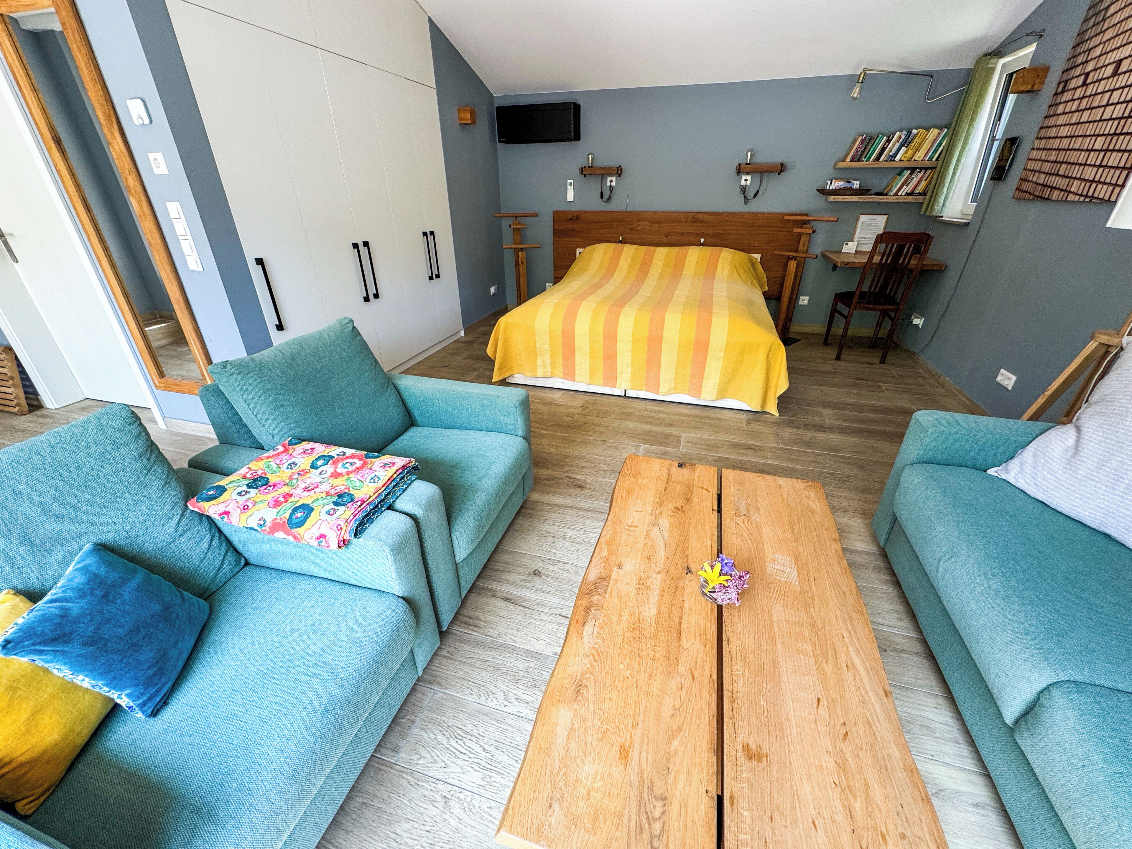Un dormitorio moderno con una cama grande, dos sofás, una mesa de centro de madera y una estantería.