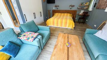 Un dormitorio moderno con una cama grande, dos sofás, una mesa de centro de madera y una estantería.