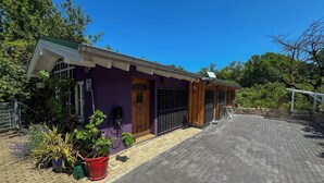 A purple building with a wooden door, a black gate, and potted plants in front. - Ferienwohnung Esswiese (Weimar)