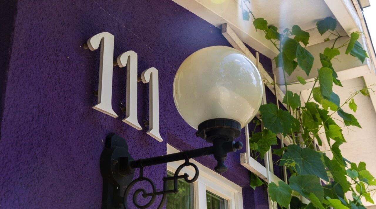Eine violette Wand mit einem weißen Schild mit der Nummer 11 und einer Straßenlaterne.
