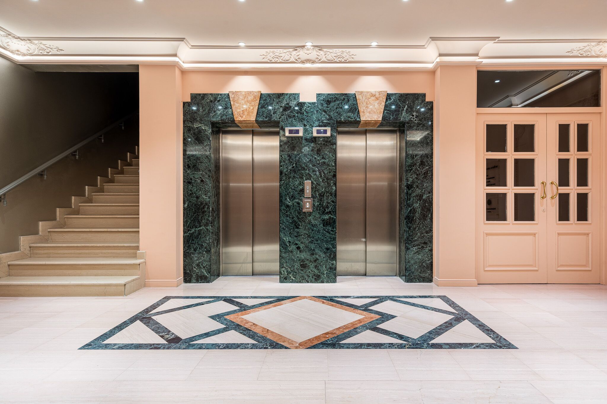 An elevator with marble walls and a geometric patterned floor.