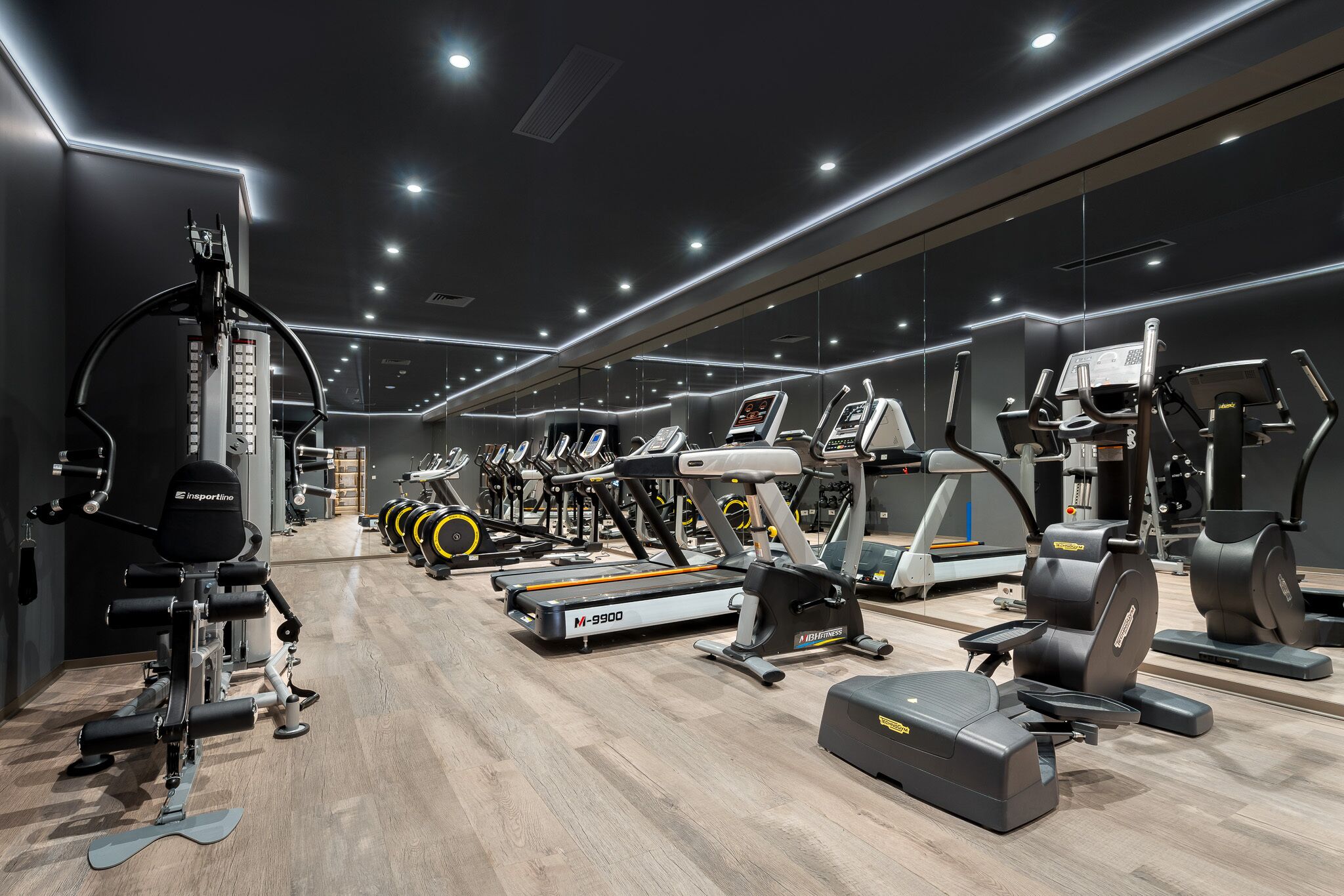 Ein modernes Fitnessstudio mit verschiedenen Trainingsgeräten, darunter Laufbänder, Crosstrainer und Kraftgeräte.
