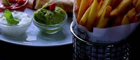 Un plato con quesadillas, papas fritas, guacamole y dos salsas para mojar.
