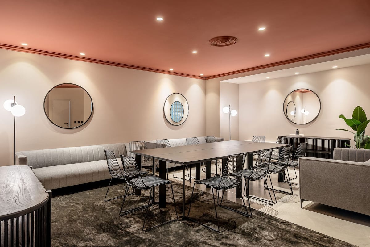 A modern conference room with a long table, multiple chairs, a sofa, and a small seating area.