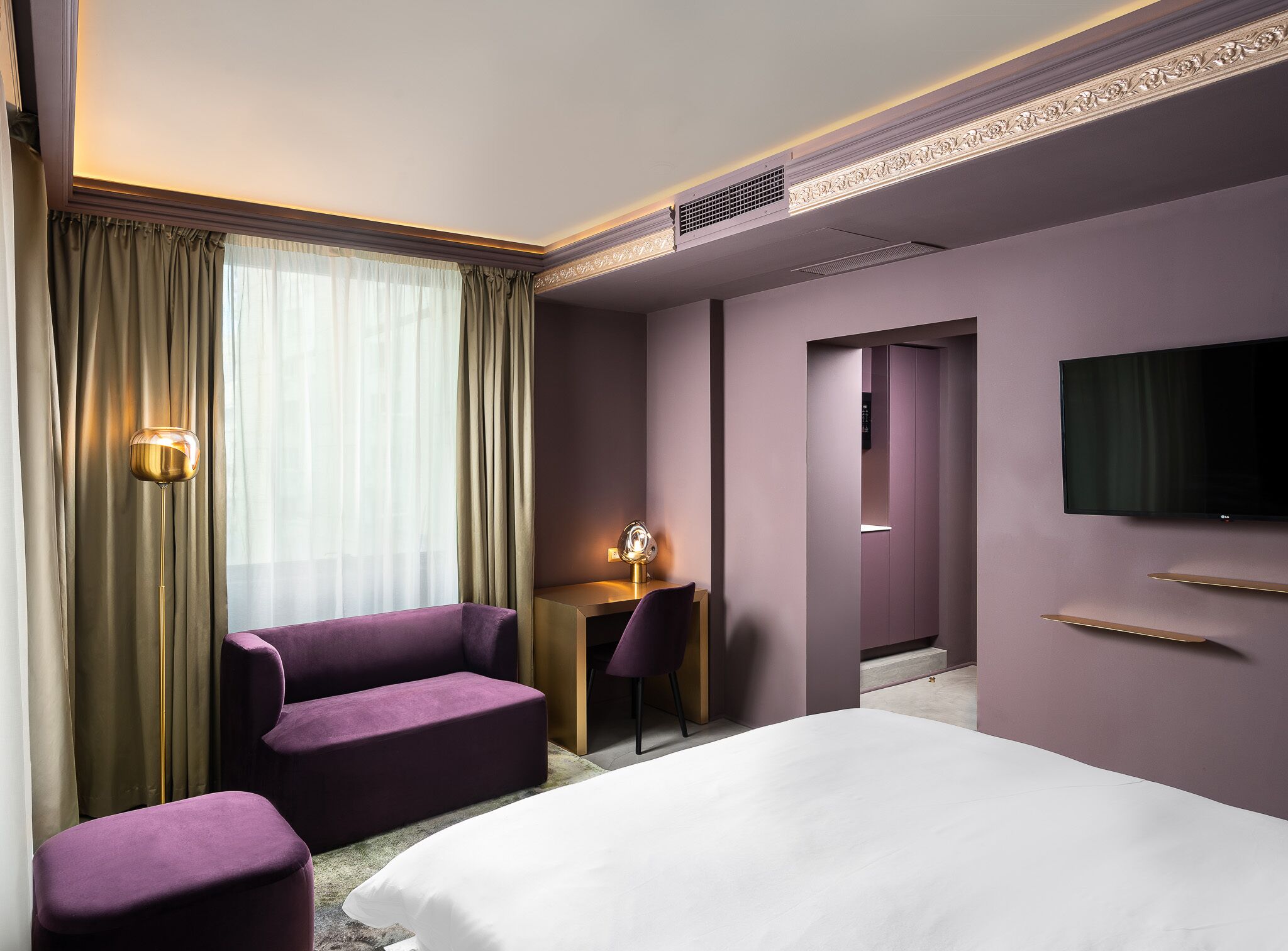 Una camera d'albergo con un letto, una scrivania, una sedia e una TV.