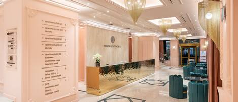 A hotel lobby with a reception desk, a directory on the left, and a seating area with round tables.