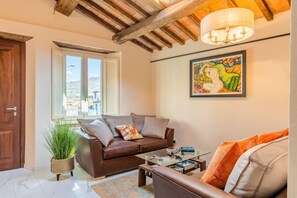Ein Wohnzimmer mit einem braunen Ledersofa, einem Glastisch und einem Bild an der Wand.