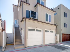 A two-story residential building with a garage, a staircase, and a small balcony.