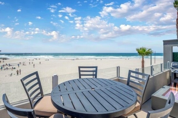 Spacious outdoor space with dining table, a grill, and panoramic sea views, perfect for alfresco meals.