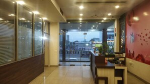 Un moderno vestíbulo de hotel con un mostrador de recepción, un ventanal y vistas a la calle.