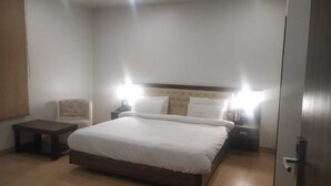 Une chambre d’hôtel avec un grand lit, deux tables de chevet, une chaise et une porte.