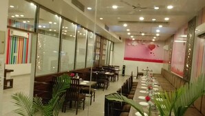 Un restaurante con varias mesas y sillas, amplias ventanas con persianas y ventiladores de techo.