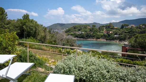 Ein Balkon mit Blick auf eine Küstenlandschaft, einschließlich eines Gewässers und umgebender Vegetation.