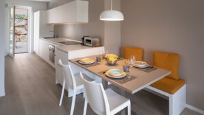 Eine moderne Küche mit weißen Schränken, einem eingebauten Backofen und einem Essbereich mit einem Holztisch, gedeckt für vier Personen.