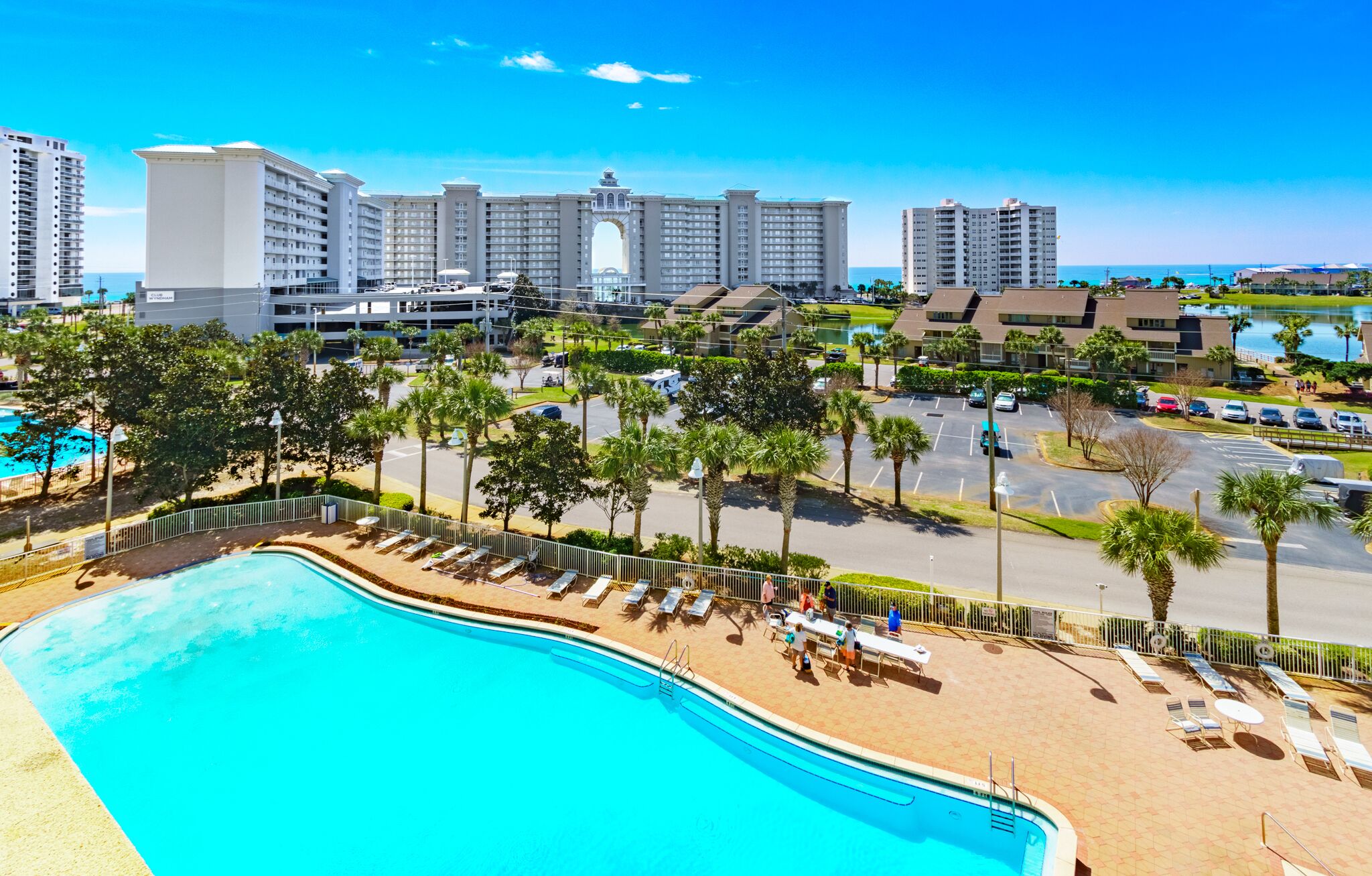 A resort with a large swimming pool, multiple hotel buildings, and a parking area.