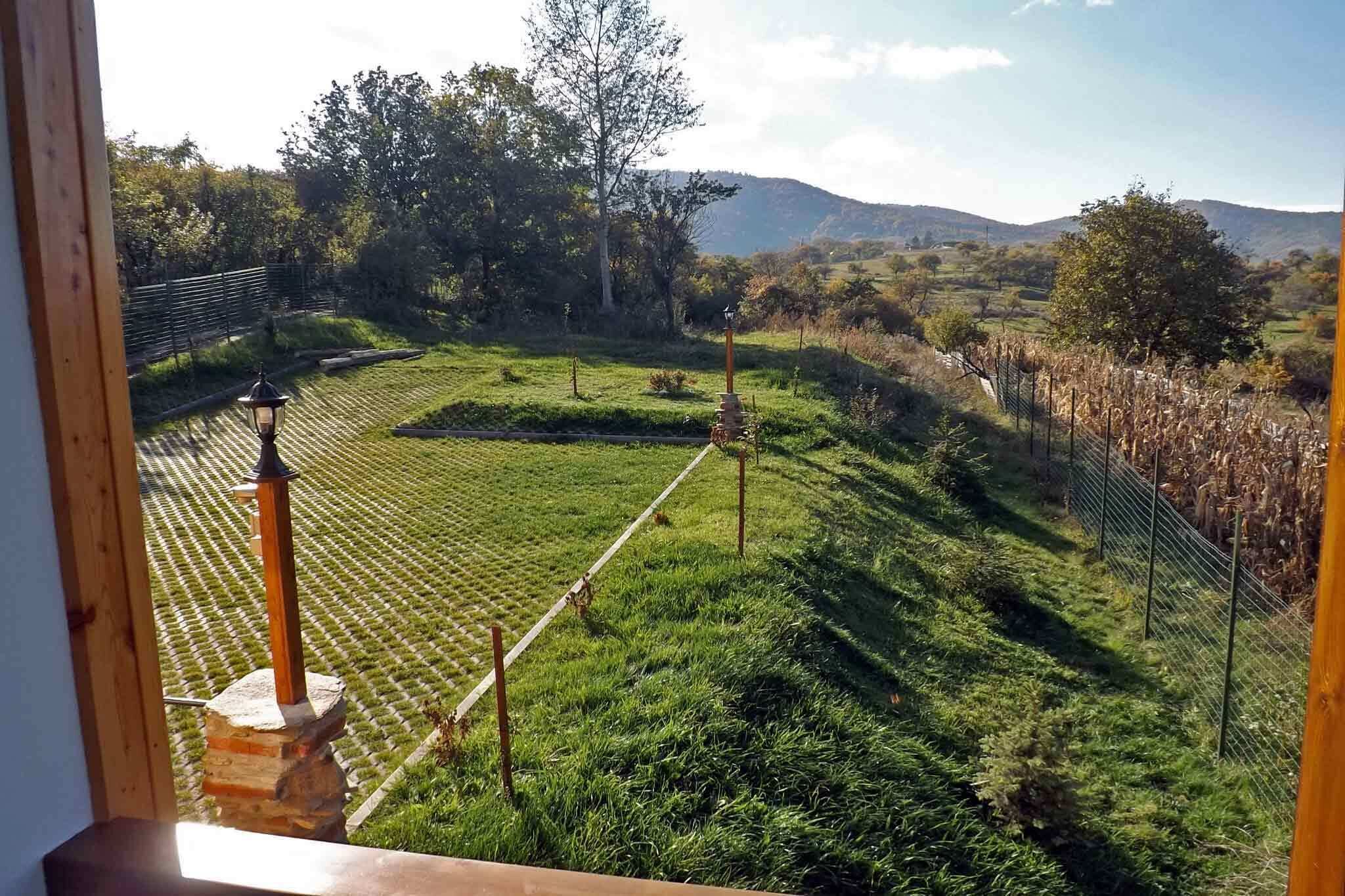 Vista di un giardino curato con vialetto in pietra, recinzione in legno e un lampione.