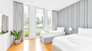 A modern hotel room with two beds, a potted plant, and a view of the outdoors.