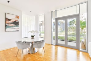 A modern dining area with a round table, grey chairs, and a vase with flowers. - Elegant 2BR with maids room and Ain View (Dubai)