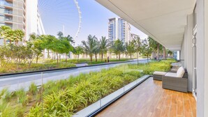 A balcony with a view of a Ferris wheel, palm trees, and modern buildings.