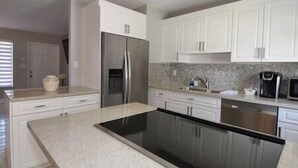 A modern kitchen with white cabinets, a stainless steel refrigerator, a black stove, and a microwave. - Cozy and Peaceful Home Near Beach (Pompano Beach)
