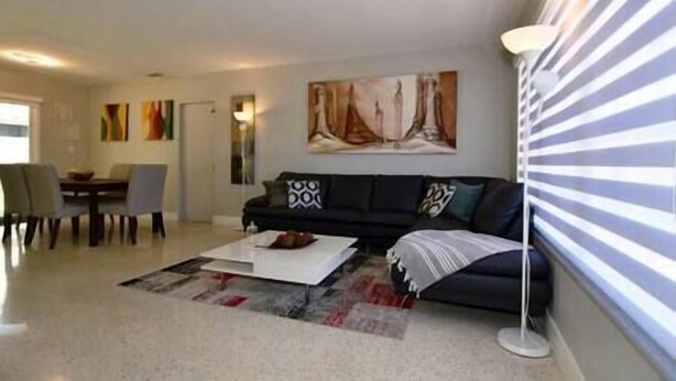 A living room with a sofa, a coffee table, and a painting on the wall. - Cozy and Peaceful Home Near Beach (Pompano Beach)