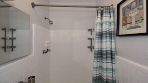 A shower area with a glass door, a metal shower rod, and a striped shower curtain. - Cozy and Peaceful Home Near Beach (Pompano Beach)